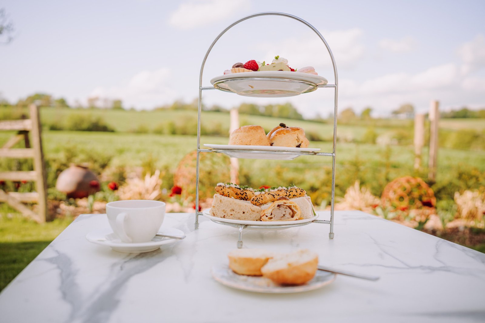 Outdoor cream tea with scones, clotted cream and tea enjoyed in the gardens at Downham Hall, dog-friendly setting