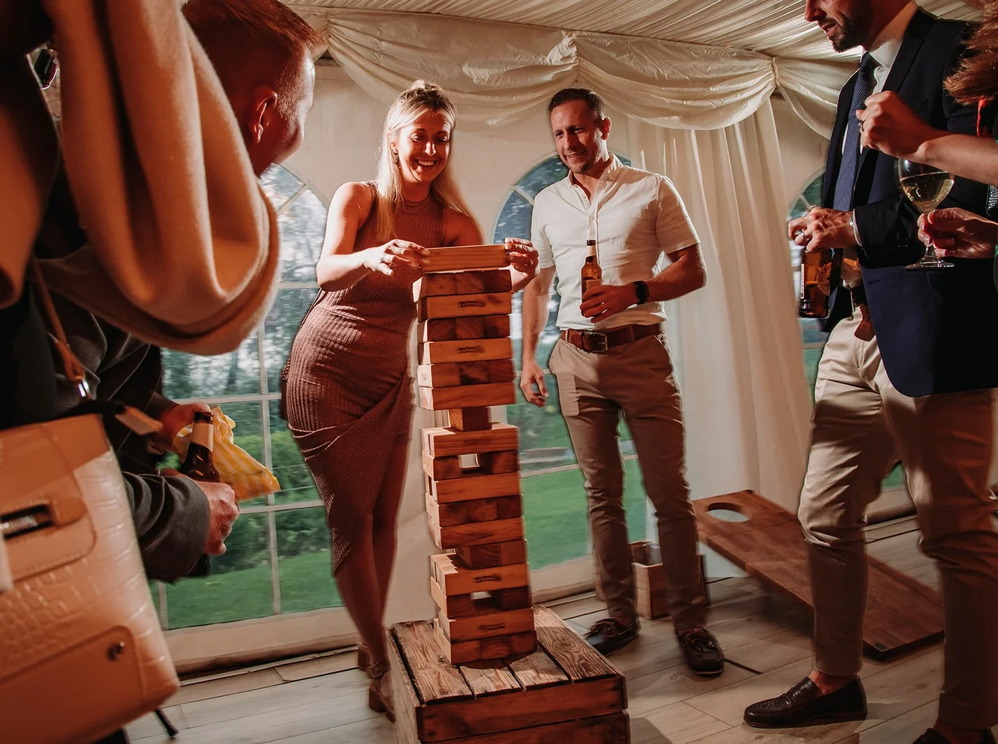 A corporate group of four colleagues laughing and playing Giant Jenga on the manicured lawn at Downham Hall in Essex.