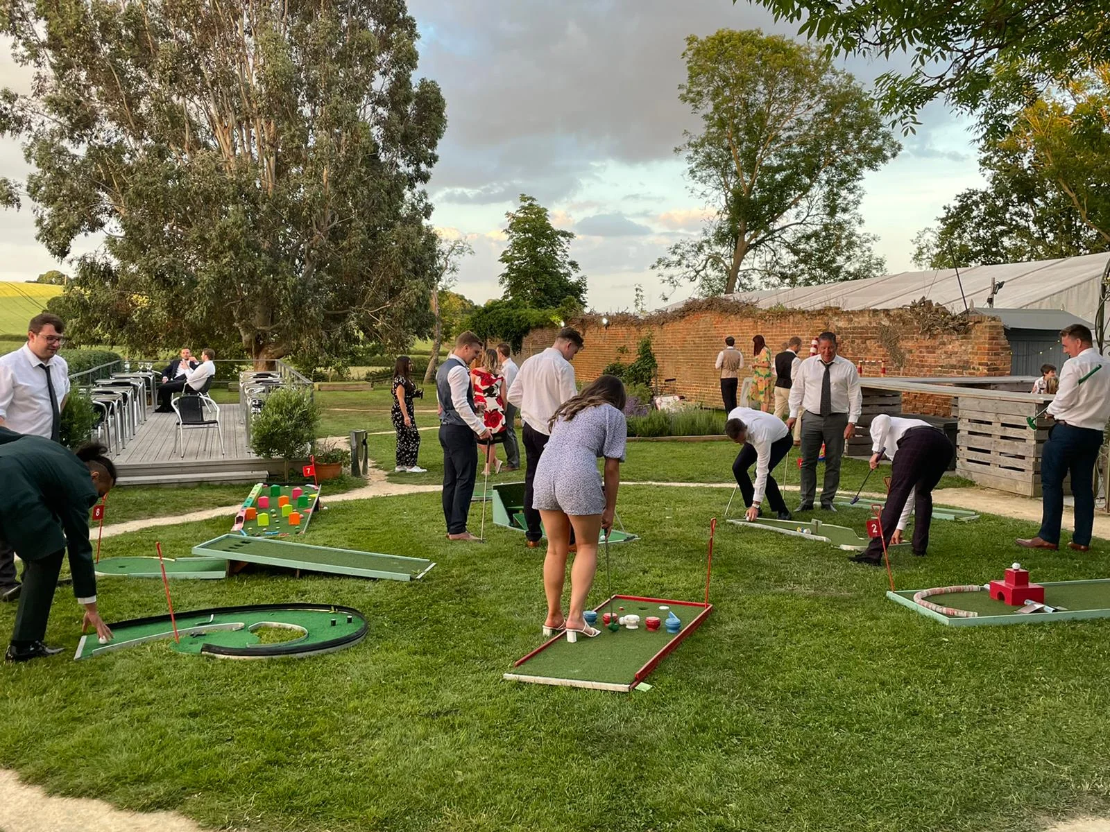 A circular, multi-hole golf putting green setup on a large landscaped lawn at Downham Hall Essex for a corporate event.