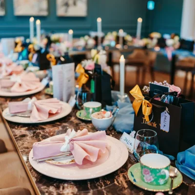 Luxury dining table setup with marble tops, pink napkins, and personalized gift bags in the De Beauvoir Suite.
